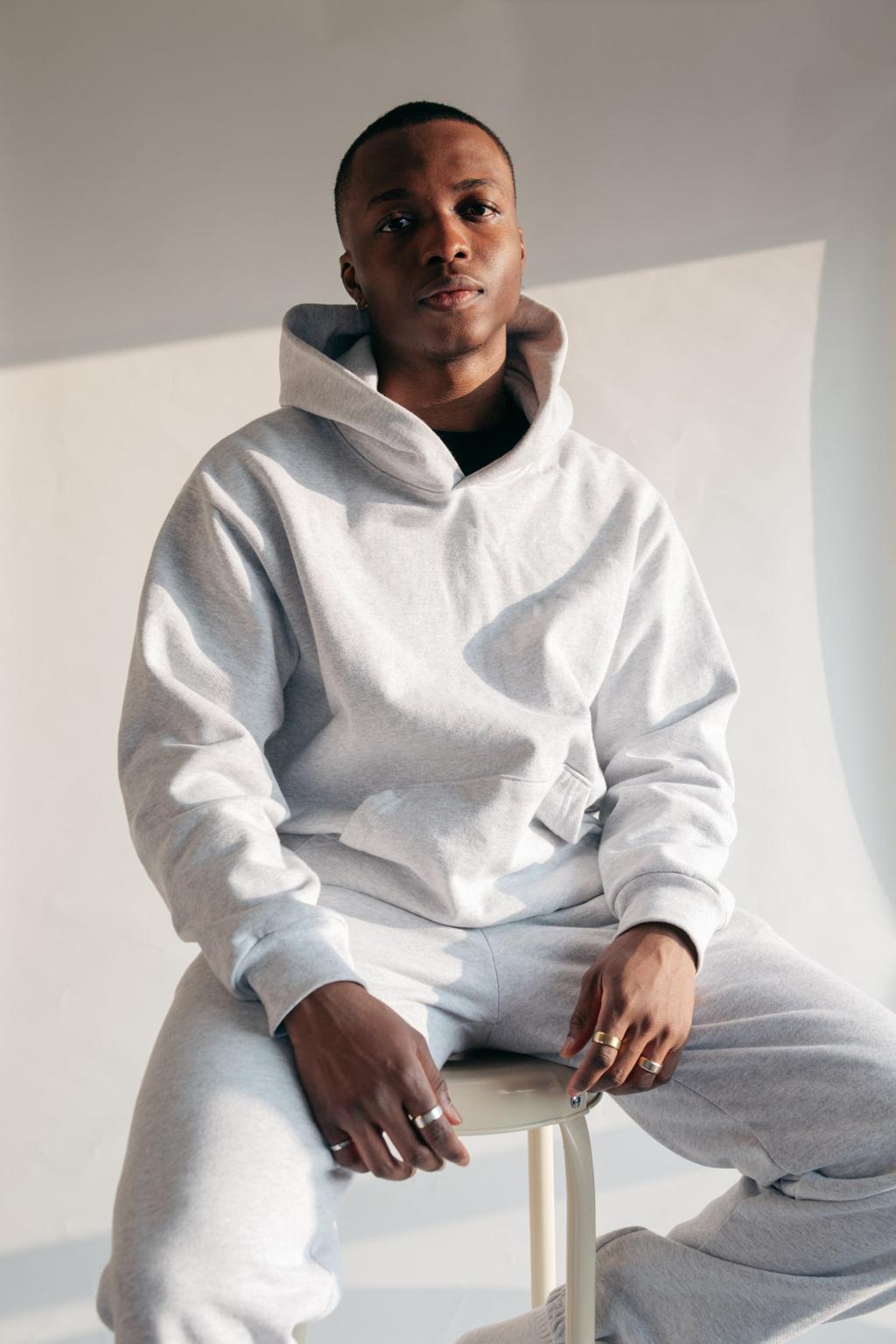 The Surrender Hoodie in Stone, worn seated