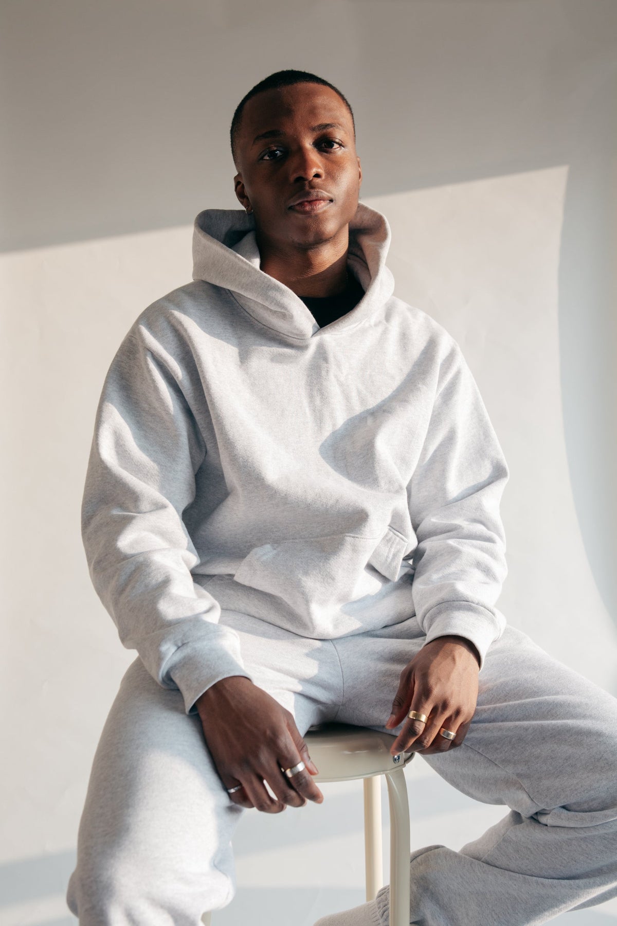 The Surrender Hoodie in Stone, worn seated